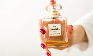 Dłoń z czerwonymi paznokciami trzyma flakonik Chanel N°5. Czy perfumy mogą się przeterminować? Ten klasyk pachnie wiecznie.