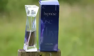 Elegancka butelka perfum Lancôme Hypnôse i jej granatowe opakowanie na drewnianym pniu. Zapach, który wciąga jak hipnoza.