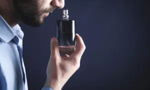 Mężczyzna wącha flakonik, szukając najbardziej trwałych perfum męskich. Elegancki zapach na cały dzień.