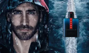 Mężczyzna z kroplami wody na twarzy obok butelki perfum Prada Luna Rossa Ocean.