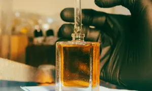 Kropla płynu, zawierającego cenną **molecule**, spada z pipety do kwadratowej buteleczki.