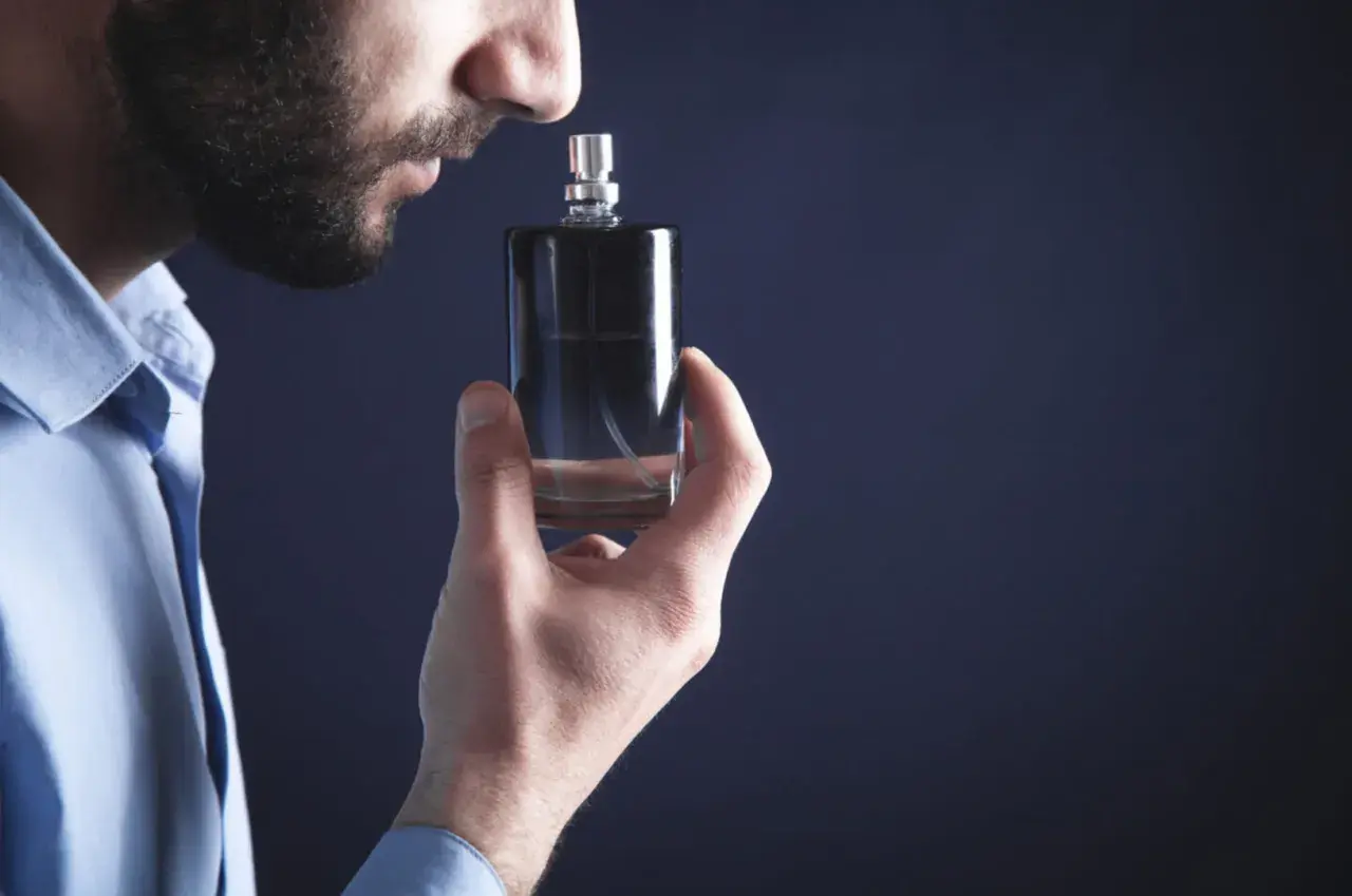 Mężczyzna wącha flakonik, szukając najbardziej trwałych perfum męskich. Elegancki zapach na cały dzień.