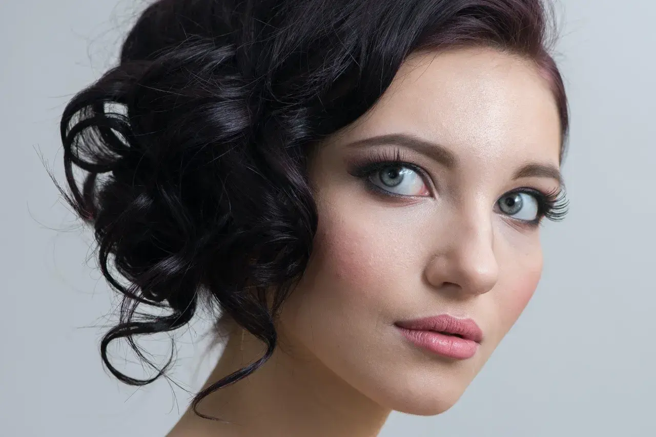 Delikatny makijaż na studniówkę podkreśla naturalne piękno młodej kobiety. Włosy ułożone w eleganckie fale dodają uroku.