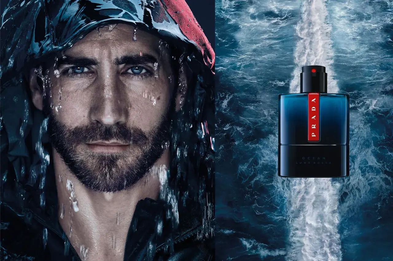 Mężczyzna z kroplami wody na twarzy obok butelki perfum Prada Luna Rossa Ocean.