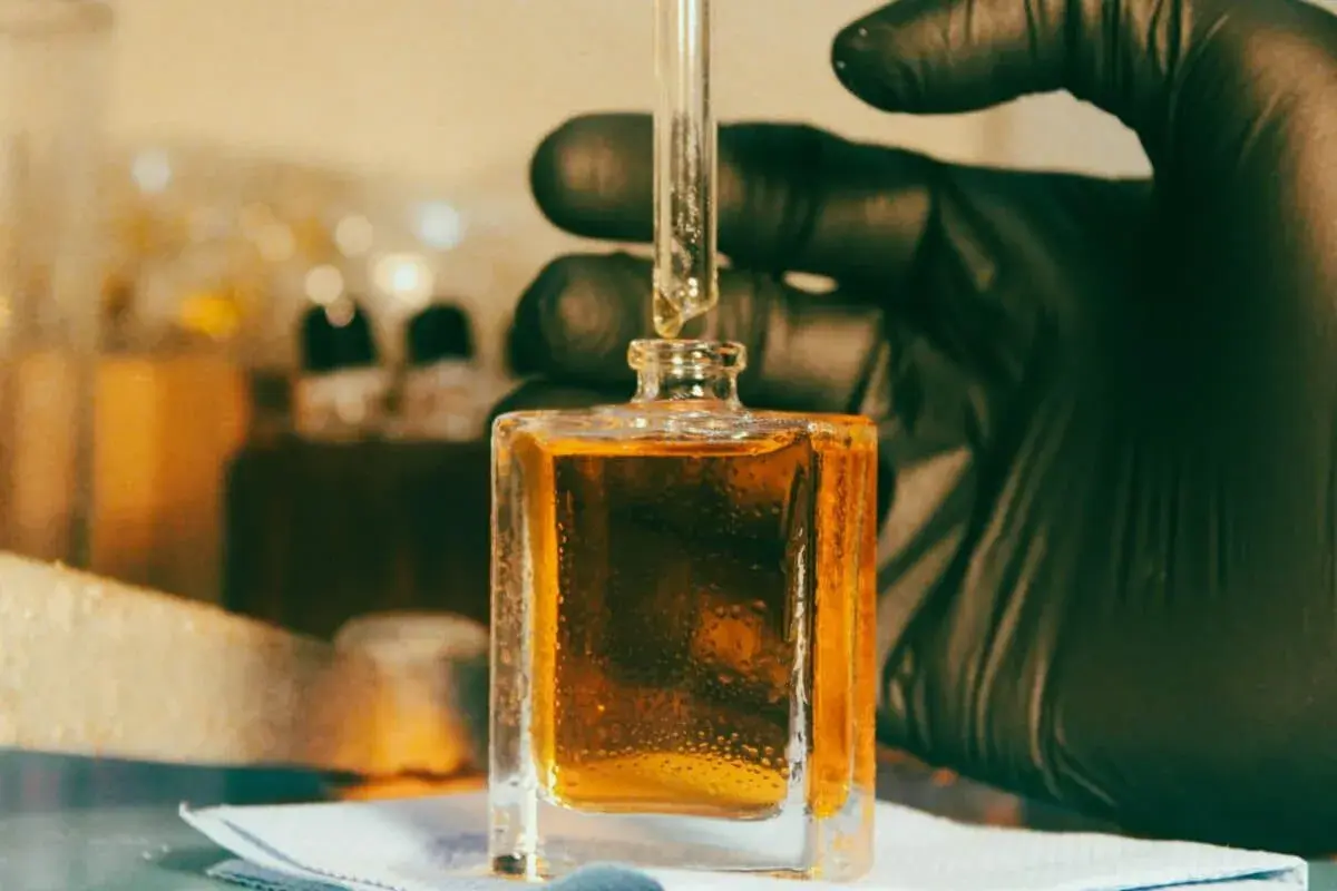 Kropla płynu, zawierającego cenną **molecule**, spada z pipety do kwadratowej buteleczki.