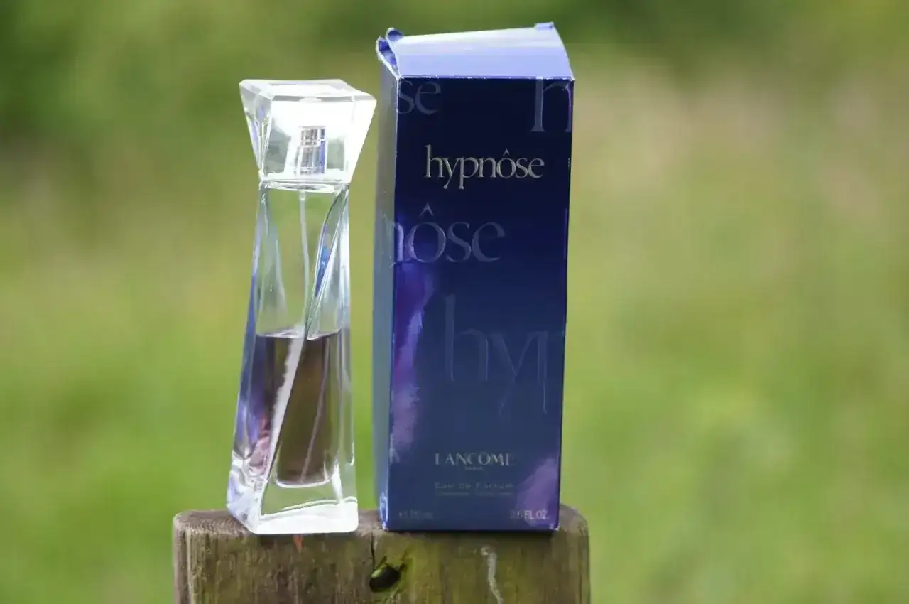 Elegancka butelka perfum Lancôme Hypnôse i jej granatowe opakowanie na drewnianym pniu. Zapach, który wciąga jak hipnoza.