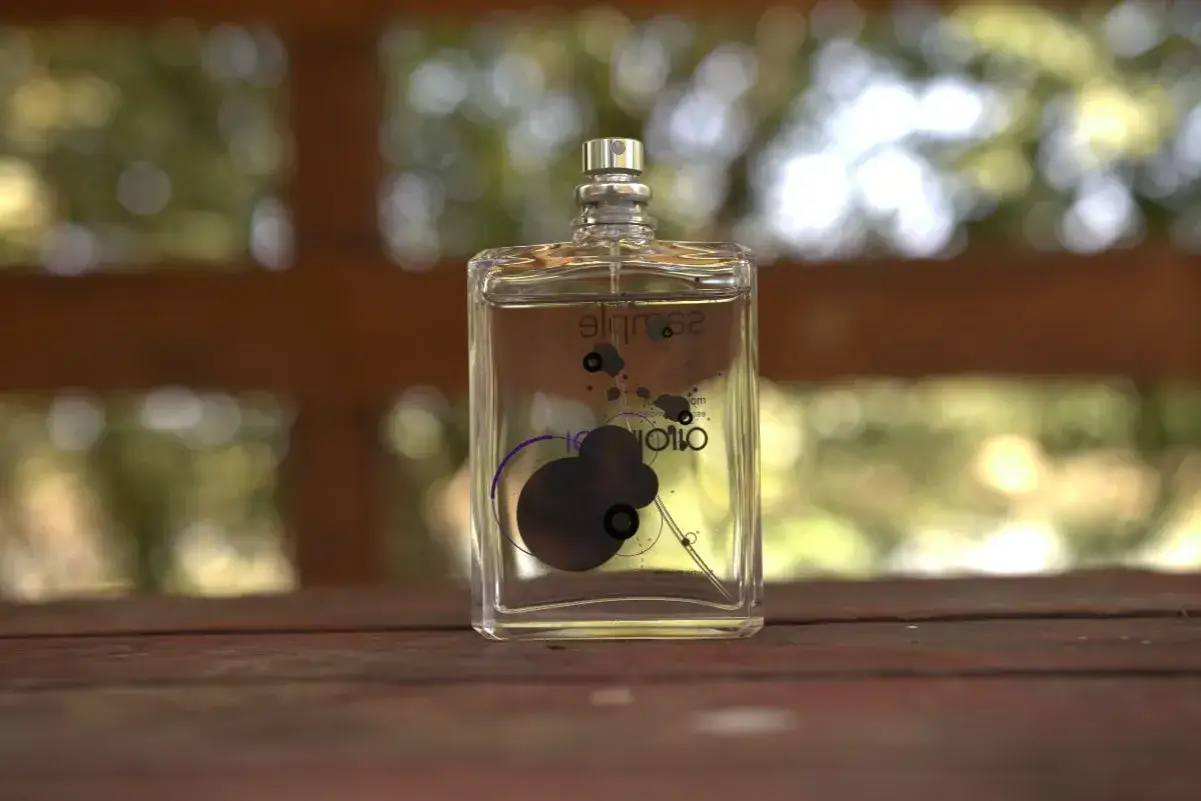 Szklana butelka perfum z fioletowym wzorem przypominającym molekułę.
