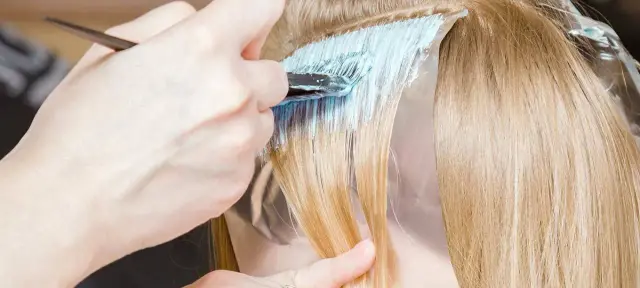 Fryzjerka nakłada rozjaśniacz na pasma włosów, przygotowując je do uzyskania efektu perłowy beż Loreal.
